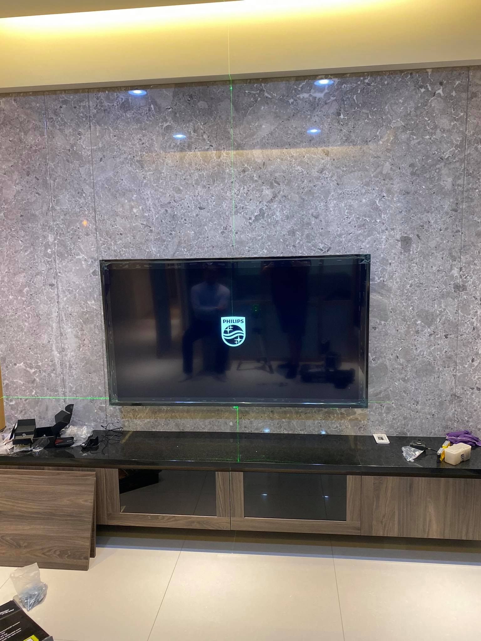 石紋牆面上安裝完成的壁掛電視，畫面水平置中